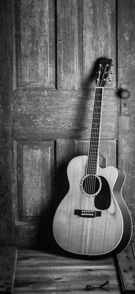 Guitarra acústica sobre puerta de madera