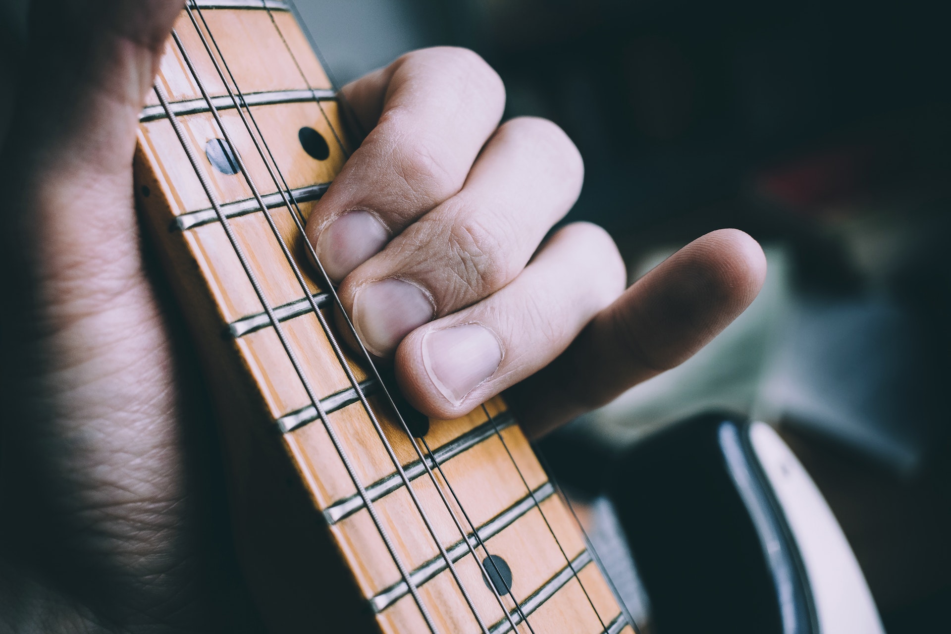 Vista de cerca de la mano de una persona tocando guitarra